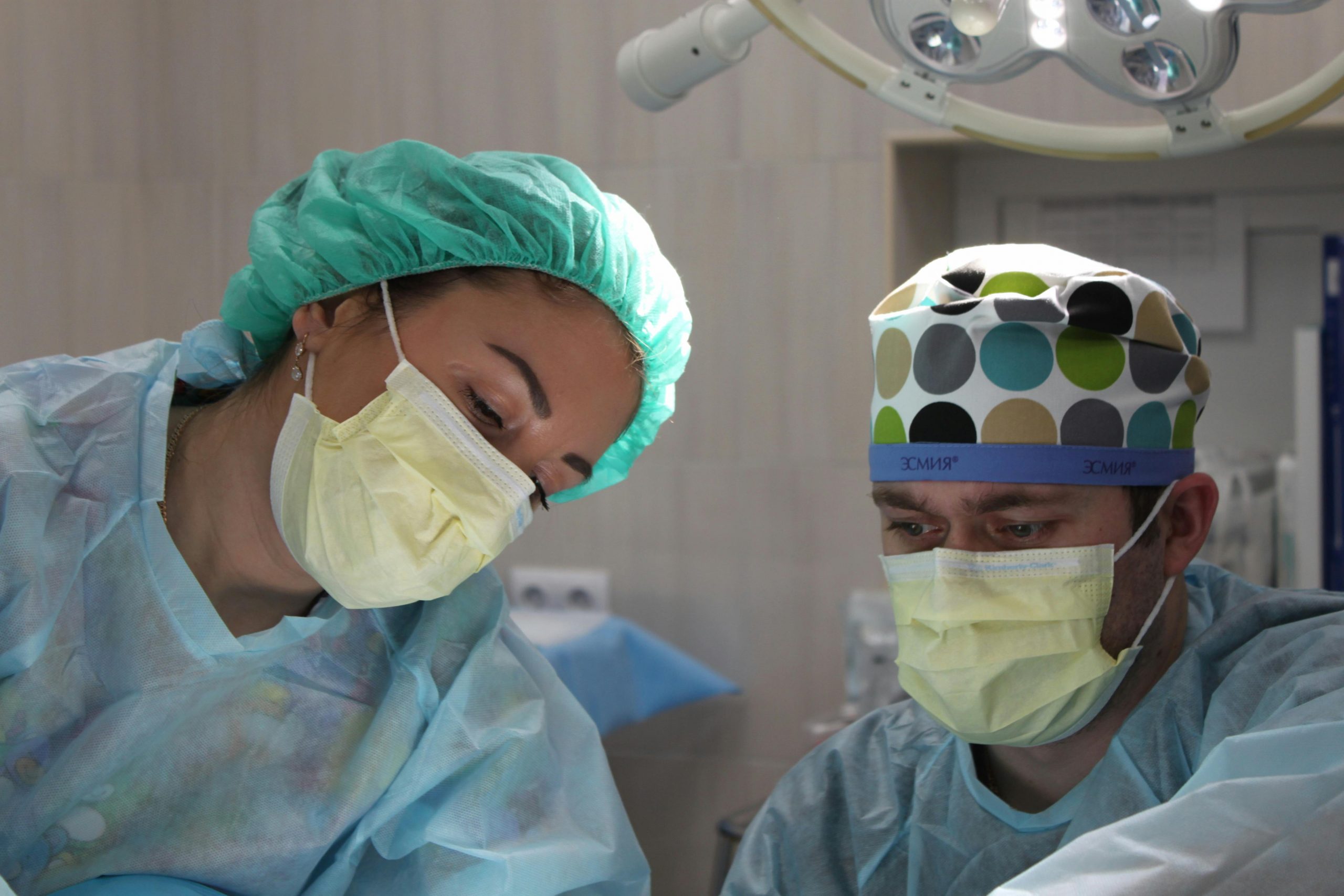 two cosmetic surgeons wearing yellow face masks during a procedure