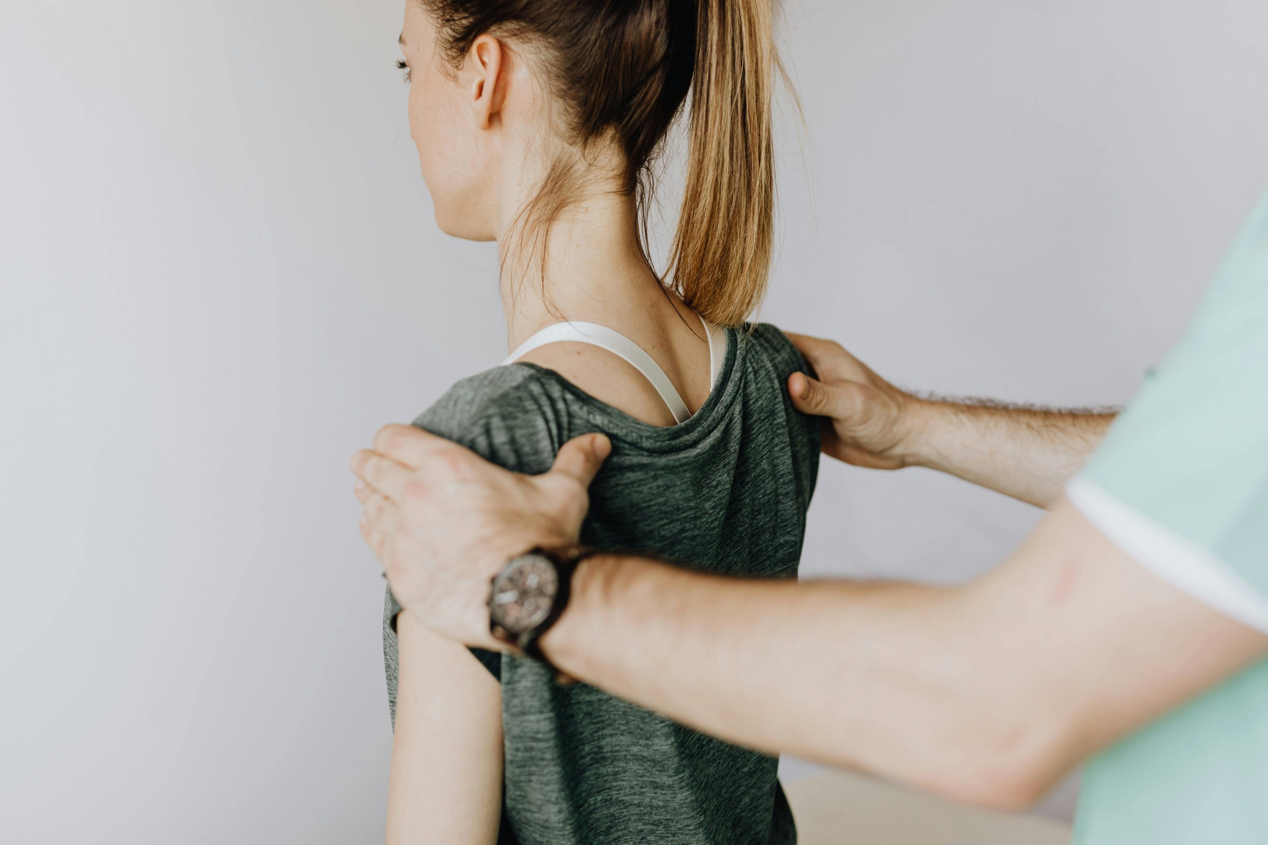 medical practitioner applying pressure to a patient's shoulder blades