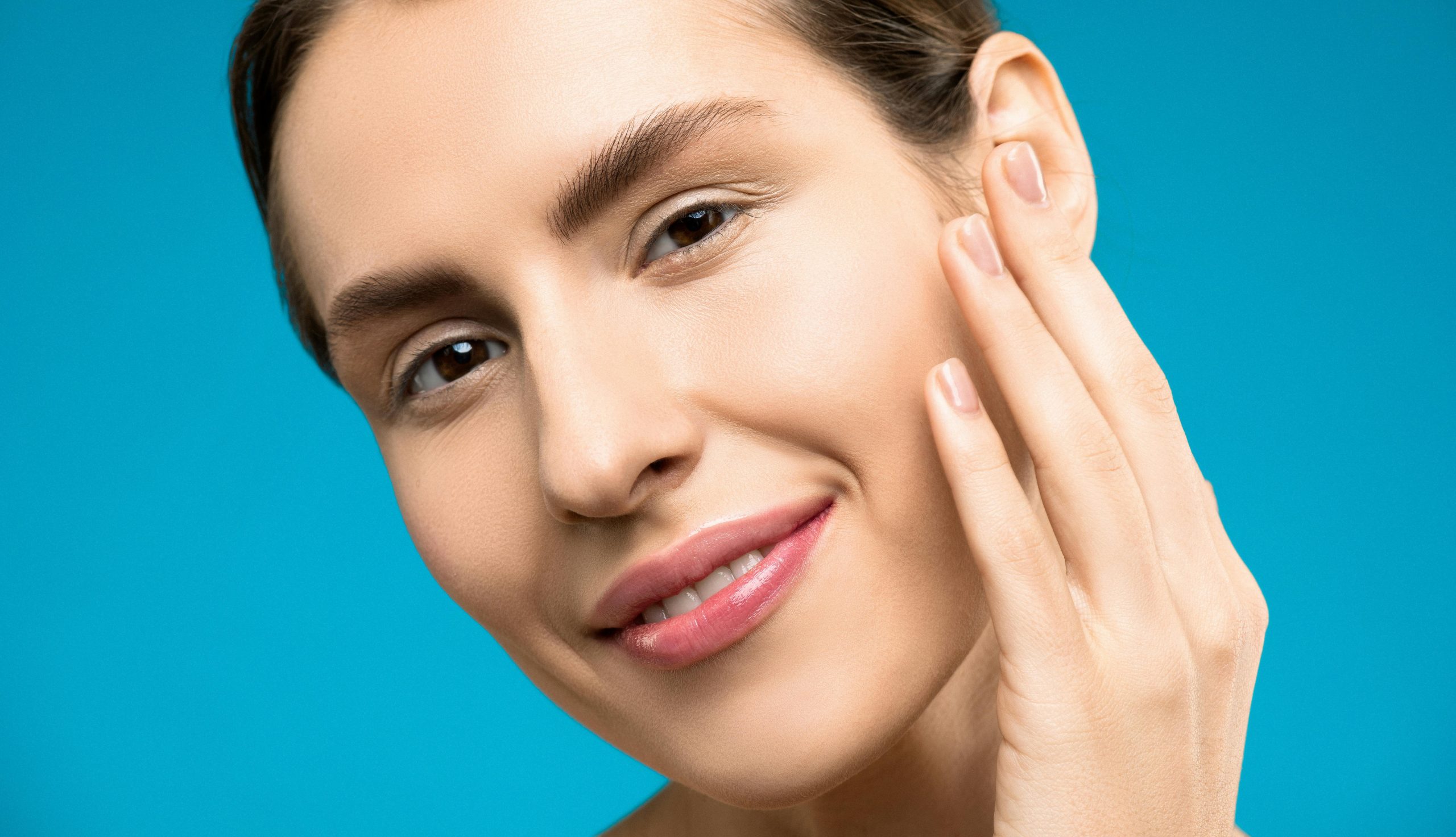 smiling woman with radiant skin gently touching her cheek