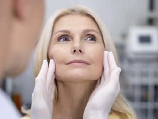 cosmetic surgeon gently lifting a patient's facial skin, evaluating for a facelift
