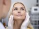 cosmetic surgeon gently lifting a patient's facial skin, evaluating for a facelift