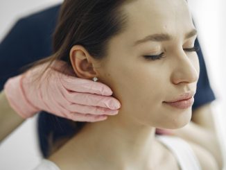 cosmetic surgeon gently touching a patient's jawline, seemingly assessing her for a facelift procedure